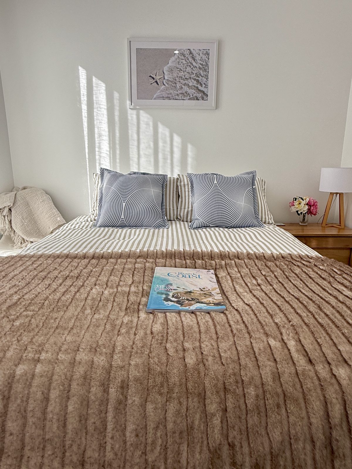 Queen bedroom with coastal artwork and morning light at Drift