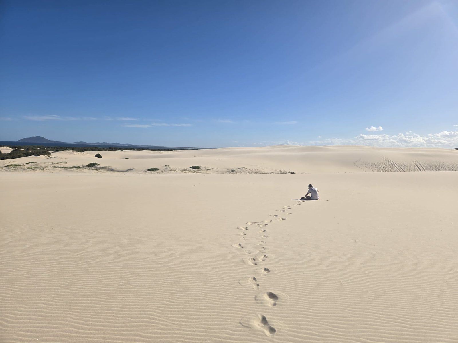 Person sitting alone on the vast white sand dunes of Mungo Brush, Myall Lakes National Park NSW