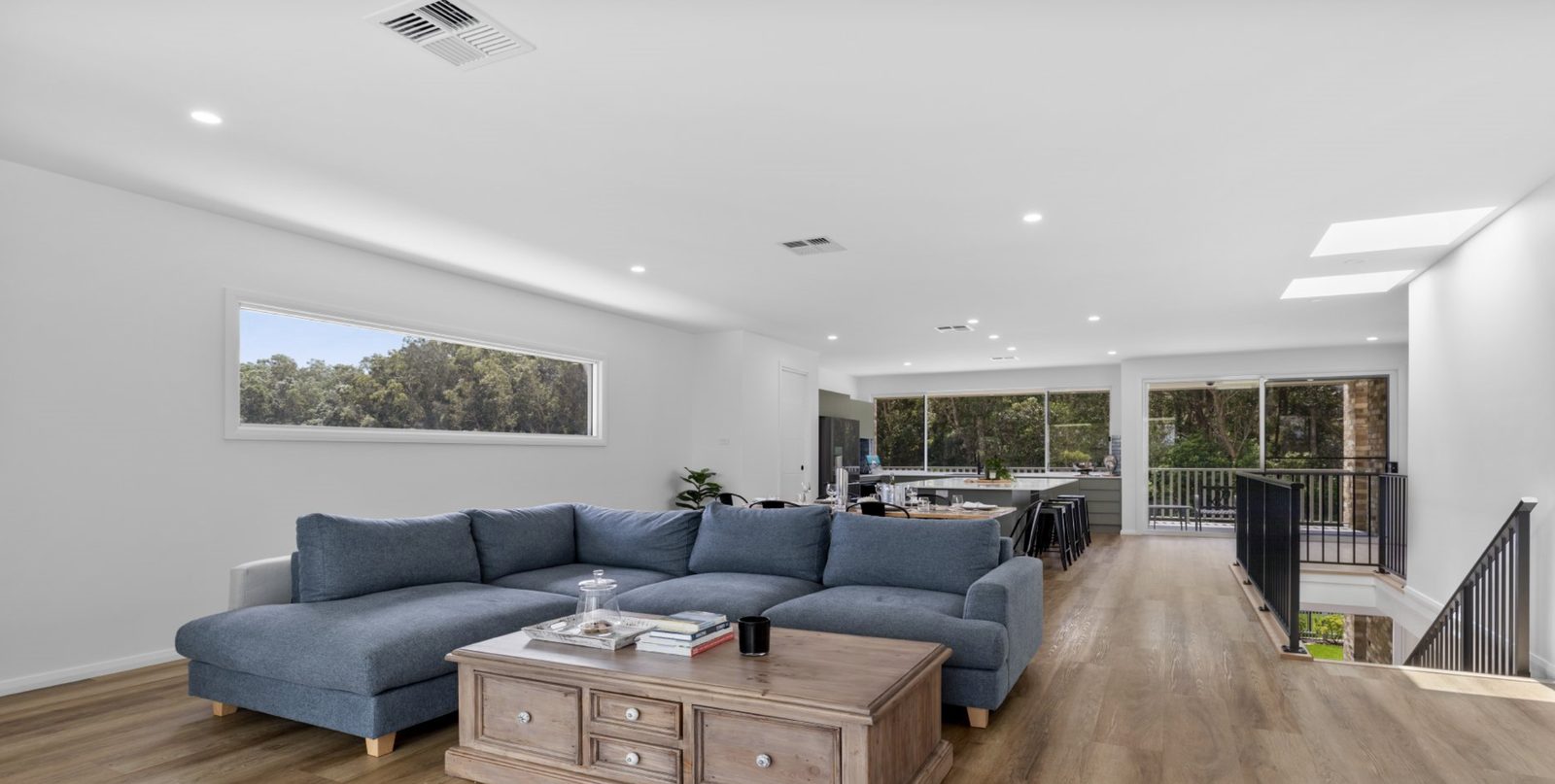 Open-plan living room at Drift, Tea Gardens — lounge, kitchen and deck beyond