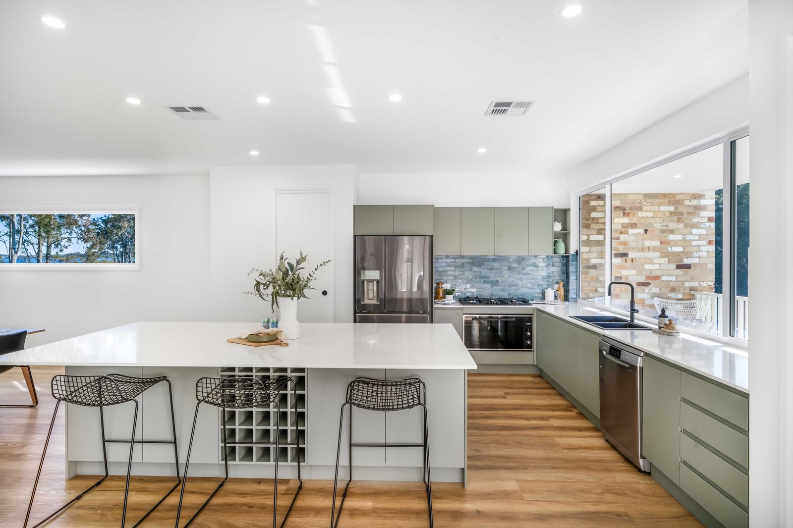 Kitchen island bench with wine rack and bar stools at Drift