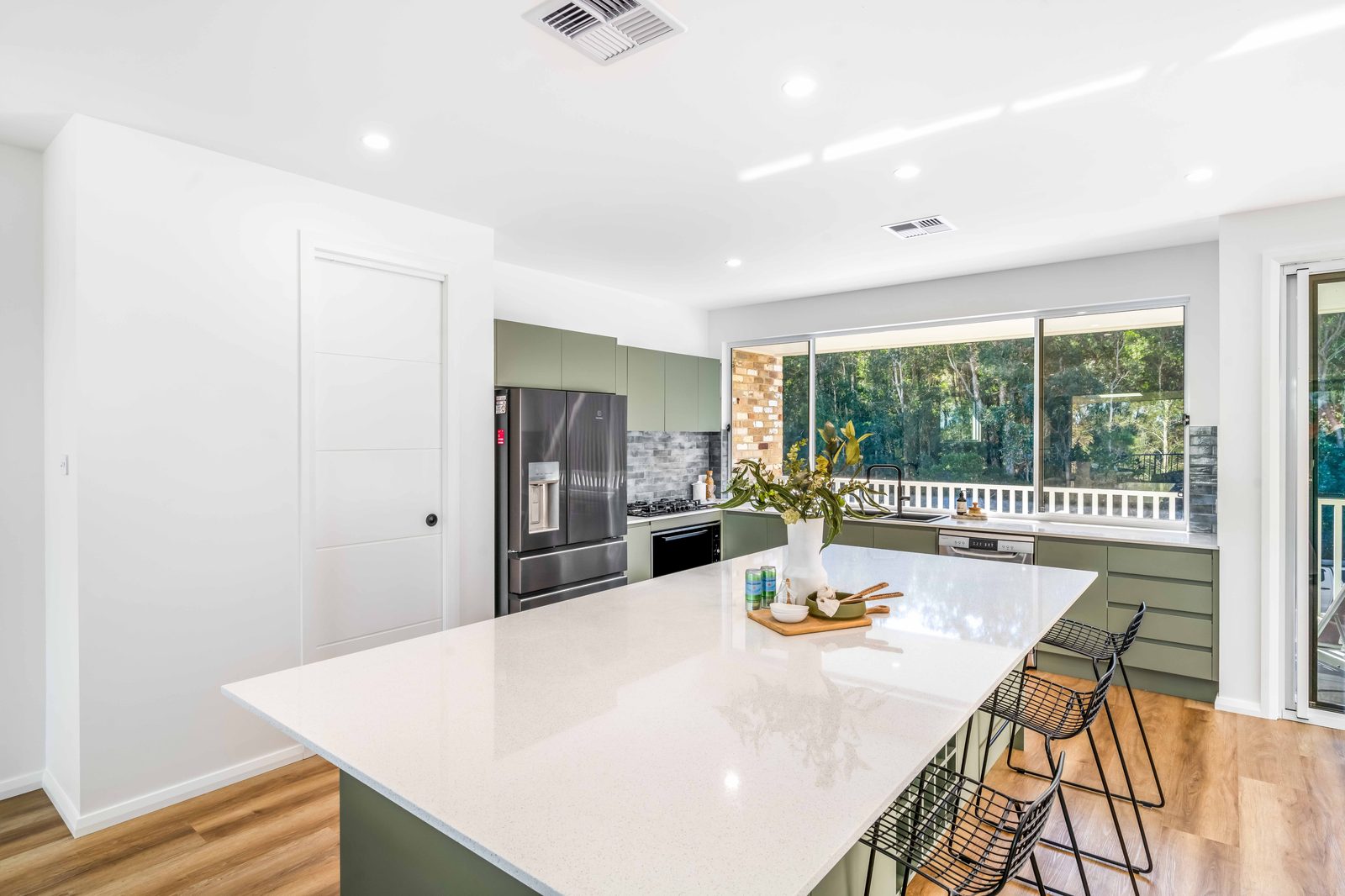 Kitchen with sage cabinetry, stone benchtop and bush outlook